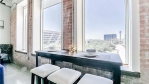 Une cuisine moderne dotée de grandes fenêtres, un coin repas avec des tabourets et une vue sur le paysage urbain.