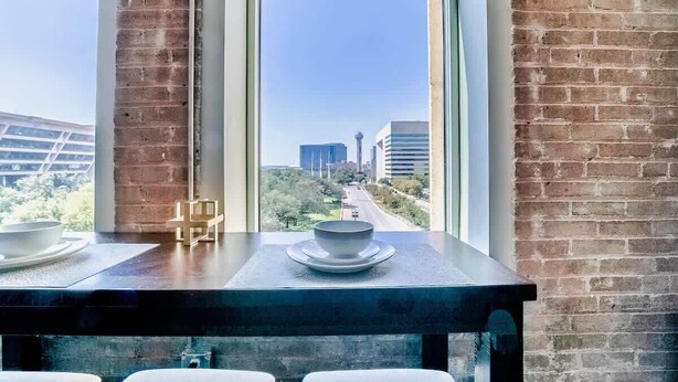 Un espace repas offrant une vue sur le paysage urbain grâce à de grandes fenêtres.