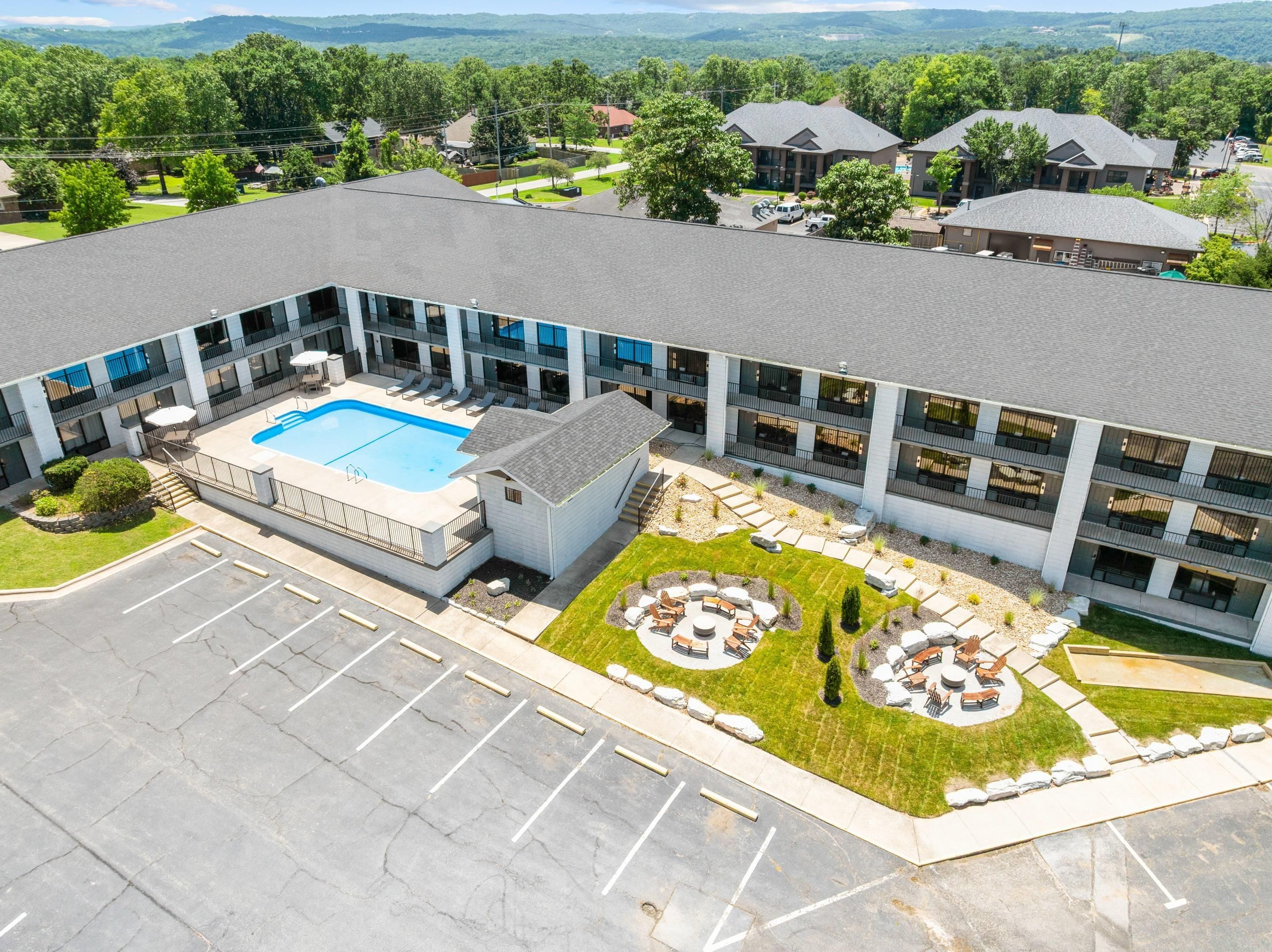 A modern building with a swimming pool, outdoor seating, and a parking lot.