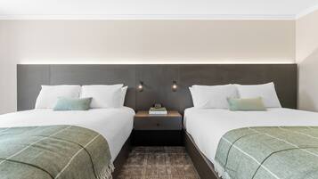 A double room with two beds, a nightstand, and a wall-mounted light fixture.