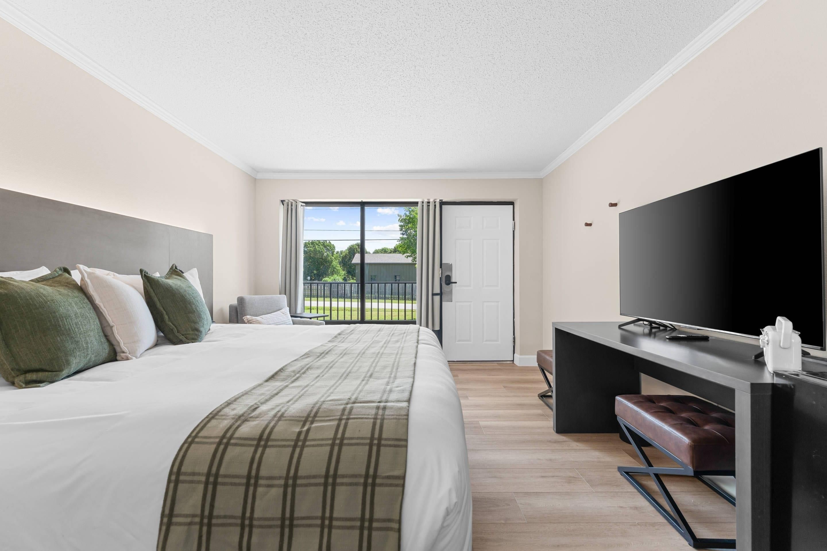 Een hotelkamer met een bed, een bureau met een televisie en uitzicht op de omgeving.