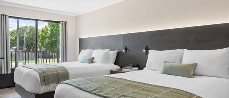 A hotel room with two beds, a large window, and a view of the outdoors.