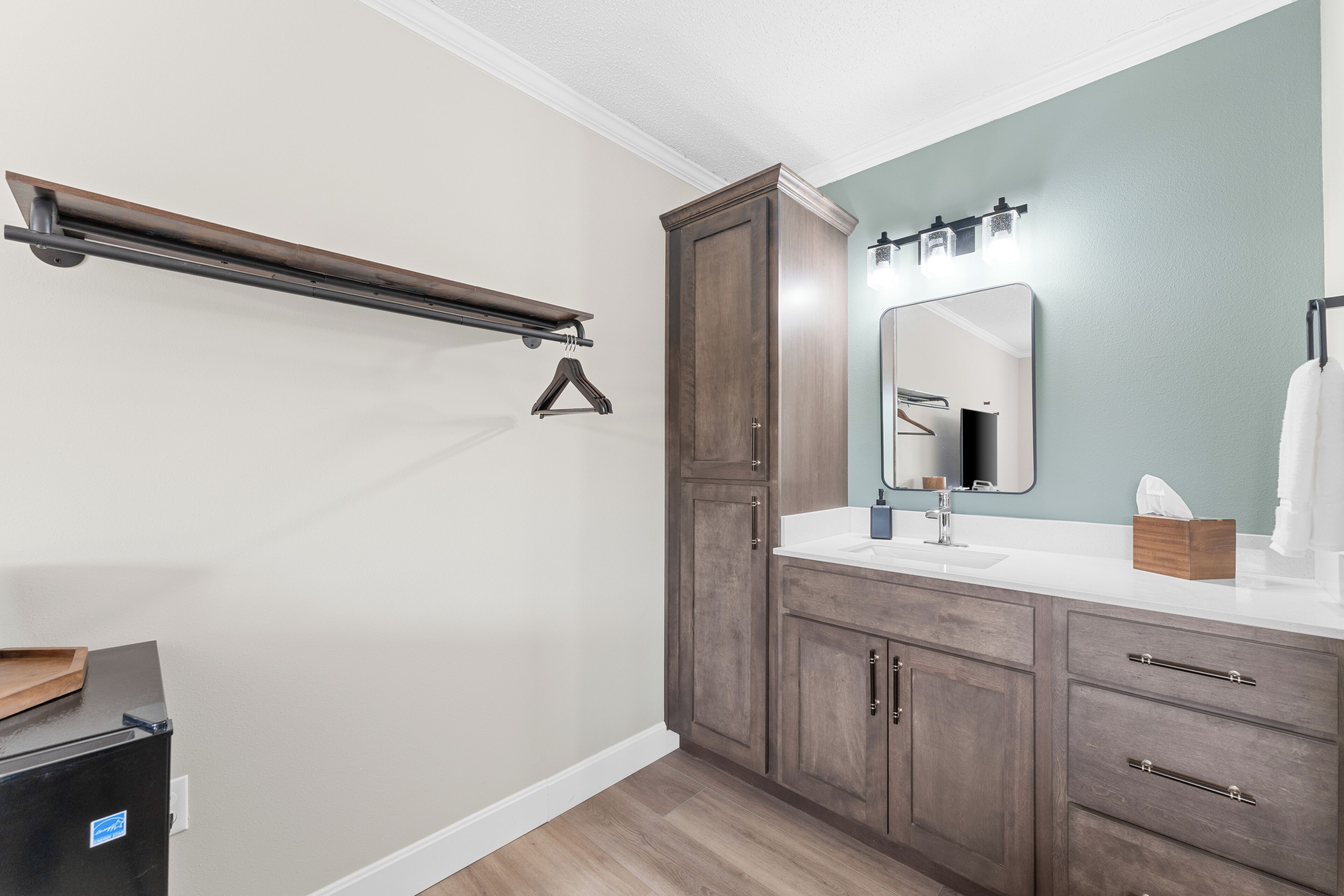 Un baño con un mueble de madera, un lavabo blanco y un espejo con iluminación.