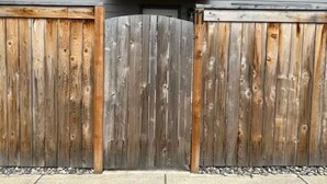 A wooden gate with a curved top, set against a grey building facade. - The Willow Stay (Vancouver)
