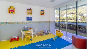 Un espace de jeux pour enfants avec des jouets, une petite table, des chaises et un tapis.