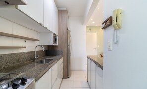 Een moderne keuken met granieten aanrechtbladen, roestvrijstalen apparatuur en een inbouwmagnetron.