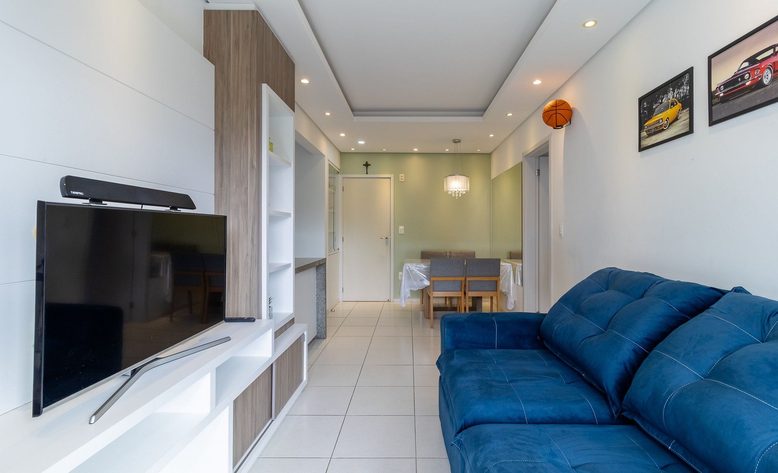 Un soggiorno moderno con una TV a schermo piatto, un divano blu e un'area pranzo con tavolo e sedie.
