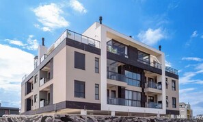 Um edifício moderno de vários andares, com varandas, janelas amplas e telhado plano.