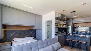 Un dormitorio moderno con cama, sofá y una pequeña zona de kitchenette.