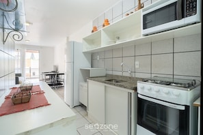 A modern kitchen with white cabinets, a granite countertop, and a built-in oven.