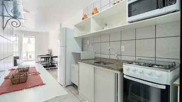 Una cocina moderna con armarios blancos, encimera de granito y horno empotrado.