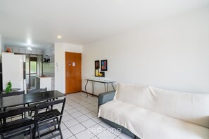 A modern living room with a sofa, a dining table with chairs, and a kitchen area with a refrigerator and a coffee machine. - Apt 300m From the Charming Praia Brava Ccu203 (Florianópolis)