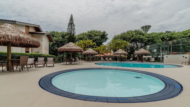 A swimming pool area with lounge chairs and thatched umbrellas. - Apt 300m From the Charming Praia Brava Ccu203 (Florianópolis)