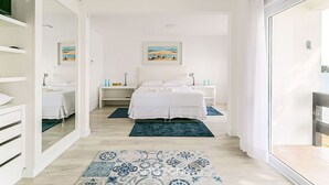 Un dormitorio moderno con una cama, mesitas de noche, un espejo y obras de arte en la pared.