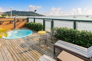 A wooden deck with a swimming pool, a small table, and chairs.
