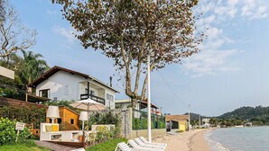 Una propiedad frente a la playa con una casa blanca, un patio con sillones de descanso y vistas al mar.