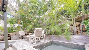 A hot tub with a wooden deck and two white chairs.