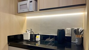 A modern kitchen with a black countertop, a microwave, a coffee maker, and a utensil holder. - Breeze (Joao Pessoa)