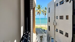 A narrow corridor with a view of a beach and palm trees. - Breeze (Joao Pessoa)