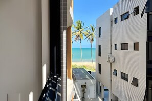 A narrow corridor with a view of a beach and palm trees. - Breeze (Joao Pessoa)
