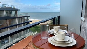 A balcony with a table set for breakfast overlooking a beach. - Breeze (Joao Pessoa)