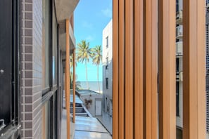 A narrow corridor with a view of a building and palm trees.