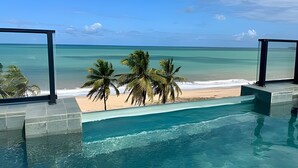 A pool with a view of a beach and palm trees. - Breeze (Joao Pessoa)