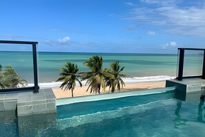 A pool with a view of a beach and palm trees. - Breeze (Joao Pessoa)
