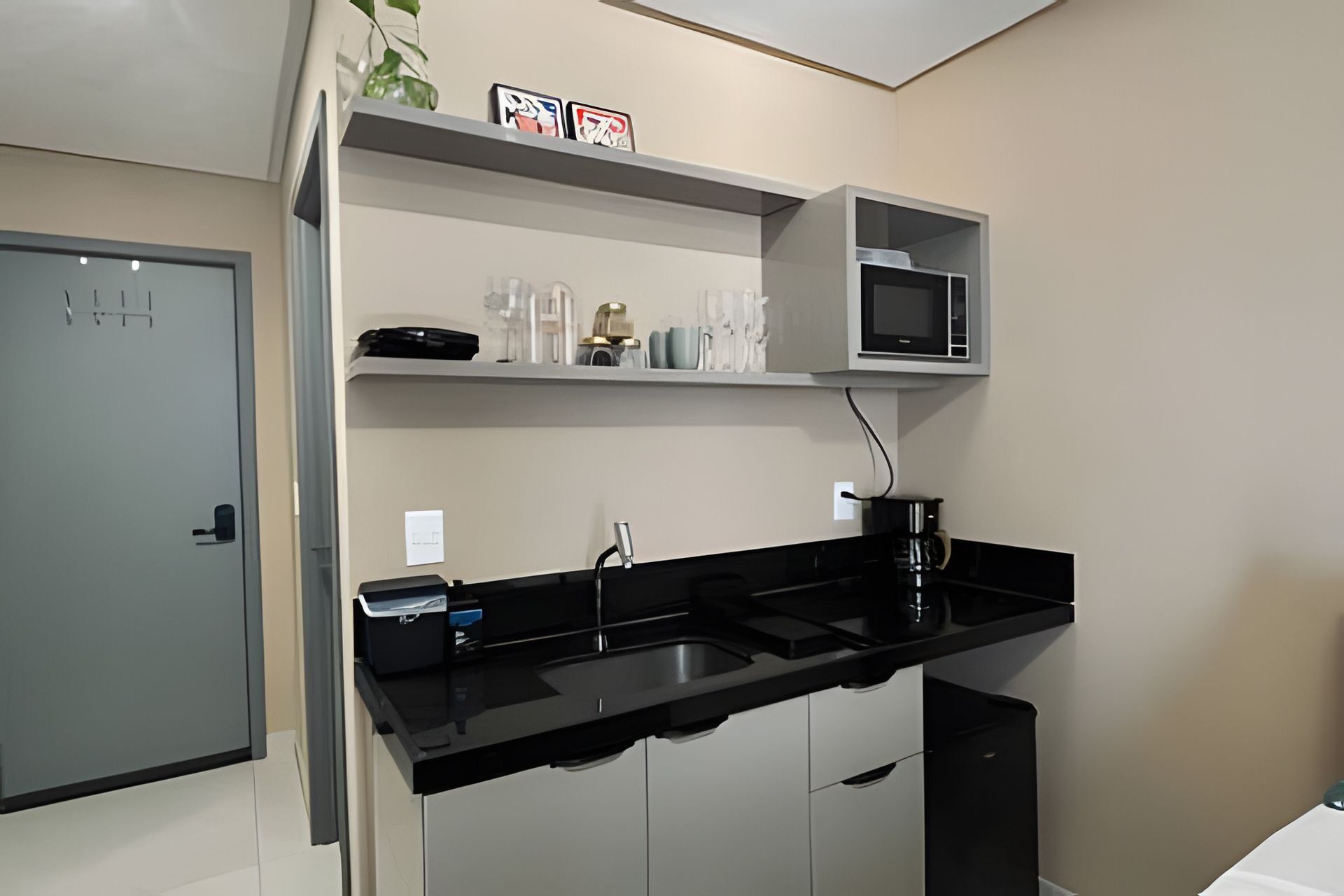 A compact kitchen with a black countertop, a microwave, and a coffee maker.