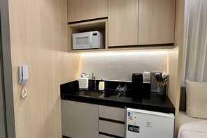 A compact kitchenette with a microwave, coffee maker, and a small refrigerator.