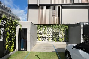 A modern building with a gated entrance, a number '540' sign, and a green wall with climbing plants.