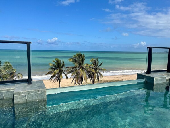 Una piscina al aire libre, sombrillas, sillones reclinables de piscina