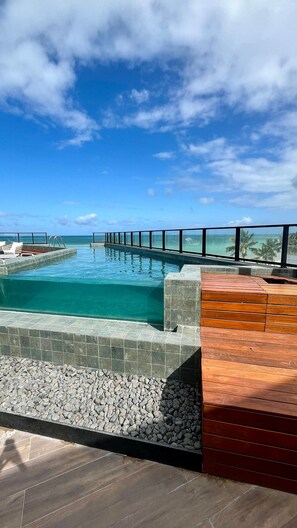Una piscina al aire libre, sombrillas, sillones reclinables de piscina