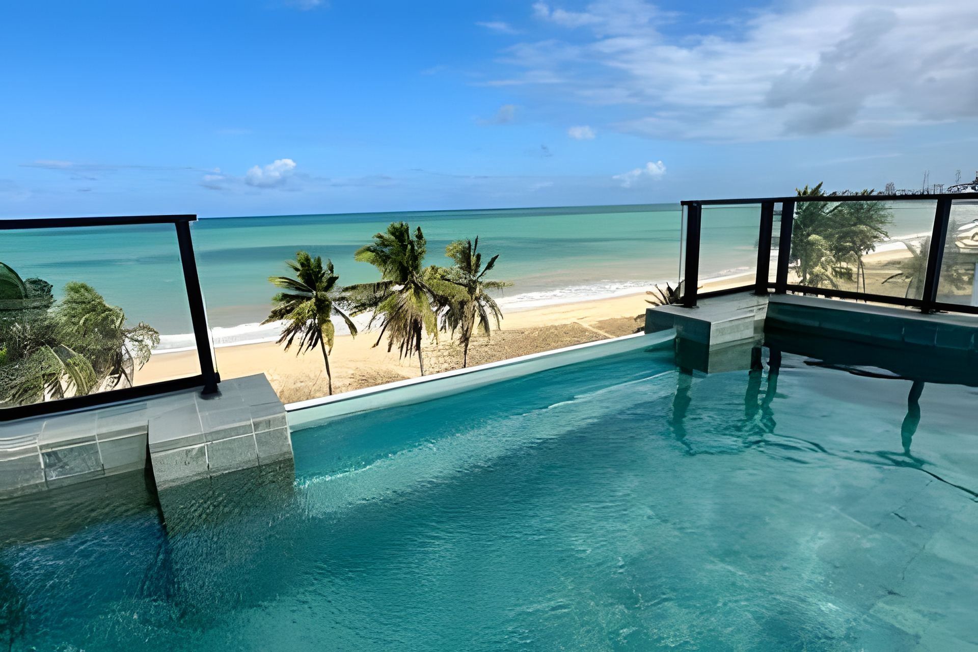 Une piscine avec vue sur une plage et des palmiers.