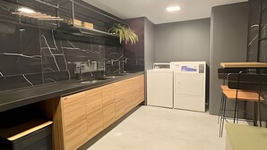 A modern kitchen with a black marble countertop, wooden cabinets, and a built-in dishwasher. - Breeze (Joao Pessoa)