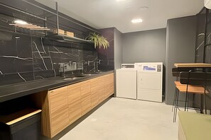 A modern kitchen with a black marble countertop, wooden cabinets, and a built-in dishwasher. - Breeze (Joao Pessoa)