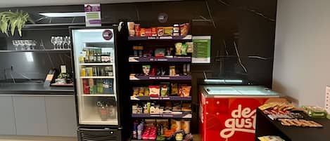 A refrigerated display case, a shelf with packaged goods, and a counter with a plant.