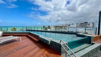 Una piscina al aire libre, sombrillas, tumbonas