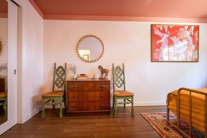 A room with a wooden dresser, two chairs, a mirror, and a large framed picture on the wall. - Central Austin Downtown Bungalow (Austin)