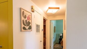 A hallway with wooden flooring, a yellow door, and a rug.