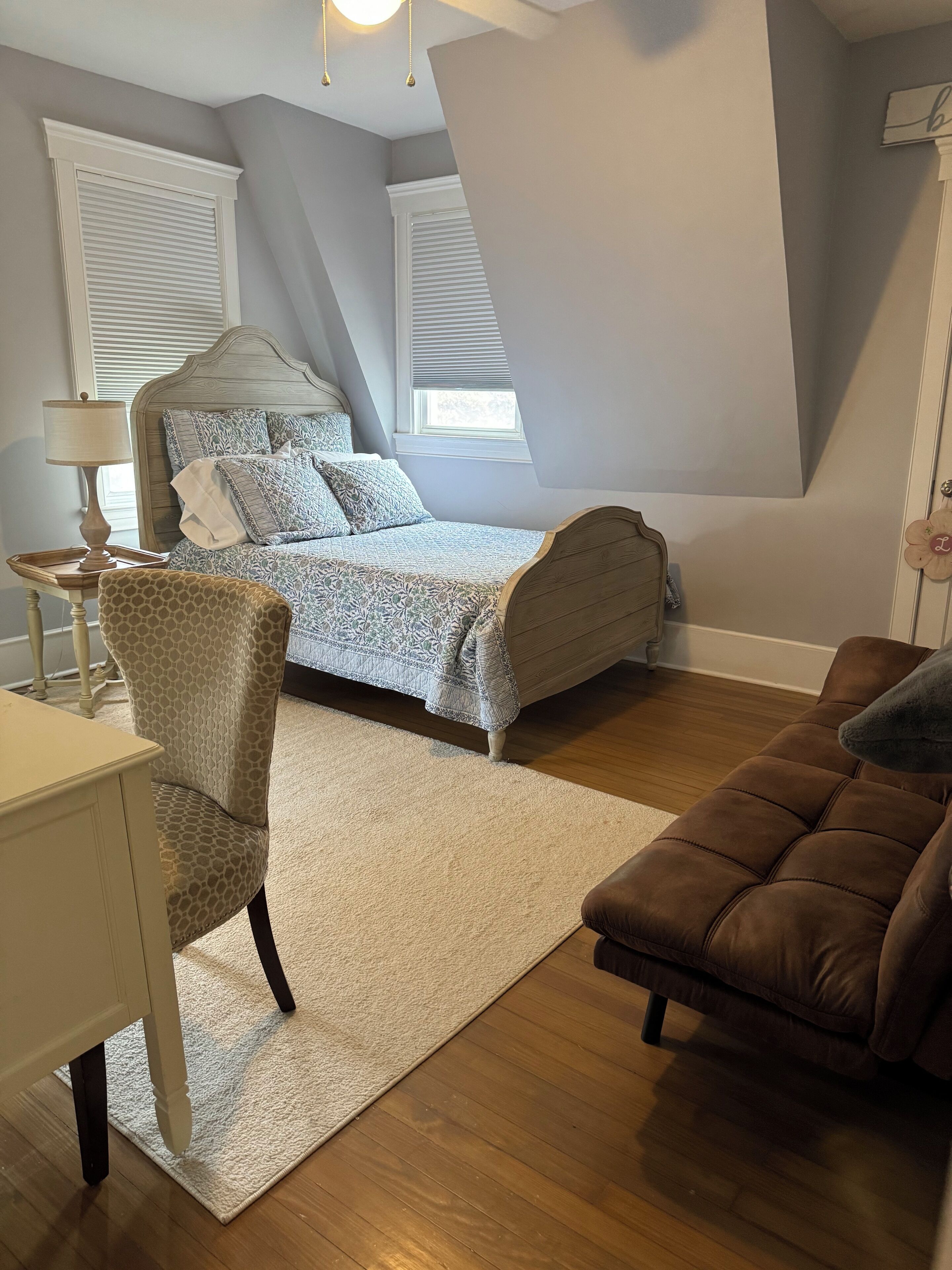 Une chambre à coucher avec un lit, une chaise, un canapé et un bureau.