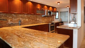 A modern kitchen with granite countertops, stainless steel appliances, and wooden cabinetry.