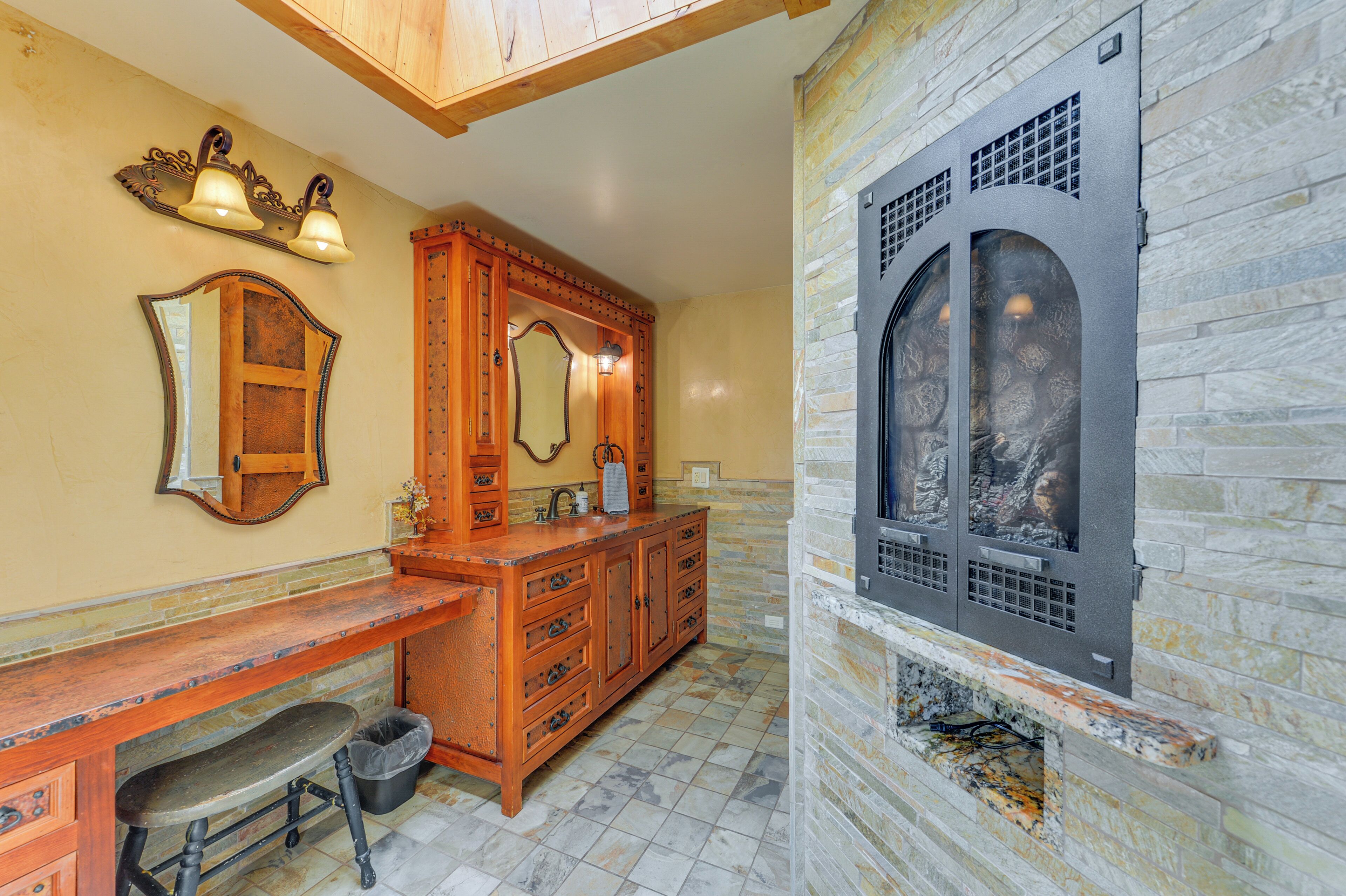 Un baño con tocador de madera, pared de piedra y chimenea integrada.
