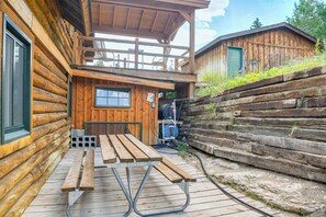 A wooden cabin with a covered porch, a picnic table, and a hose reel. - Stunning Mountain Views: Spacious Cabin in Dubois! (Dubois)