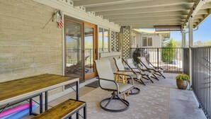 A covered patio area with a brick wall, sliding glass doors, and a seating area with chairs and a table. - Near Catalina Hiking Trails: Mtn-View Home w/ Pool (Tucson)