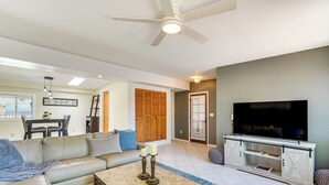 A living room with a sofa, coffee table, TV, and a dining area with chairs and a table. - Near Catalina Hiking Trails: Mtn-View Home w/ Pool (Tucson)