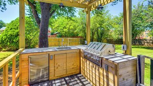 Een houten pergola buiten, met een ingebouwde barbecue en spoelruimte.