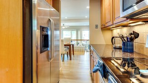 Une cuisine moderne avec des meubles en bois, des appareils électroménagers en acier inoxydable et un pare-feu en verre.