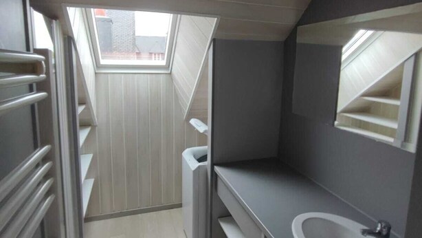 Ein modernes Badezimmer mit Oberlicht, großem Spiegel und integriertem Waschbecken.