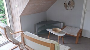 Ein Eckzimmer mit Holzboden, einem Glastisch und zwei gepolsterten Stühlen.